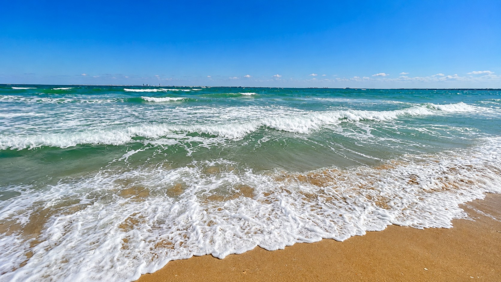 Waves washing onto the sand on a bright, sunny day