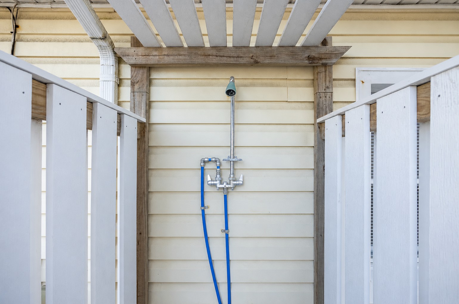 Outdoor shower fixture tucked between the privacy fence and pergola
