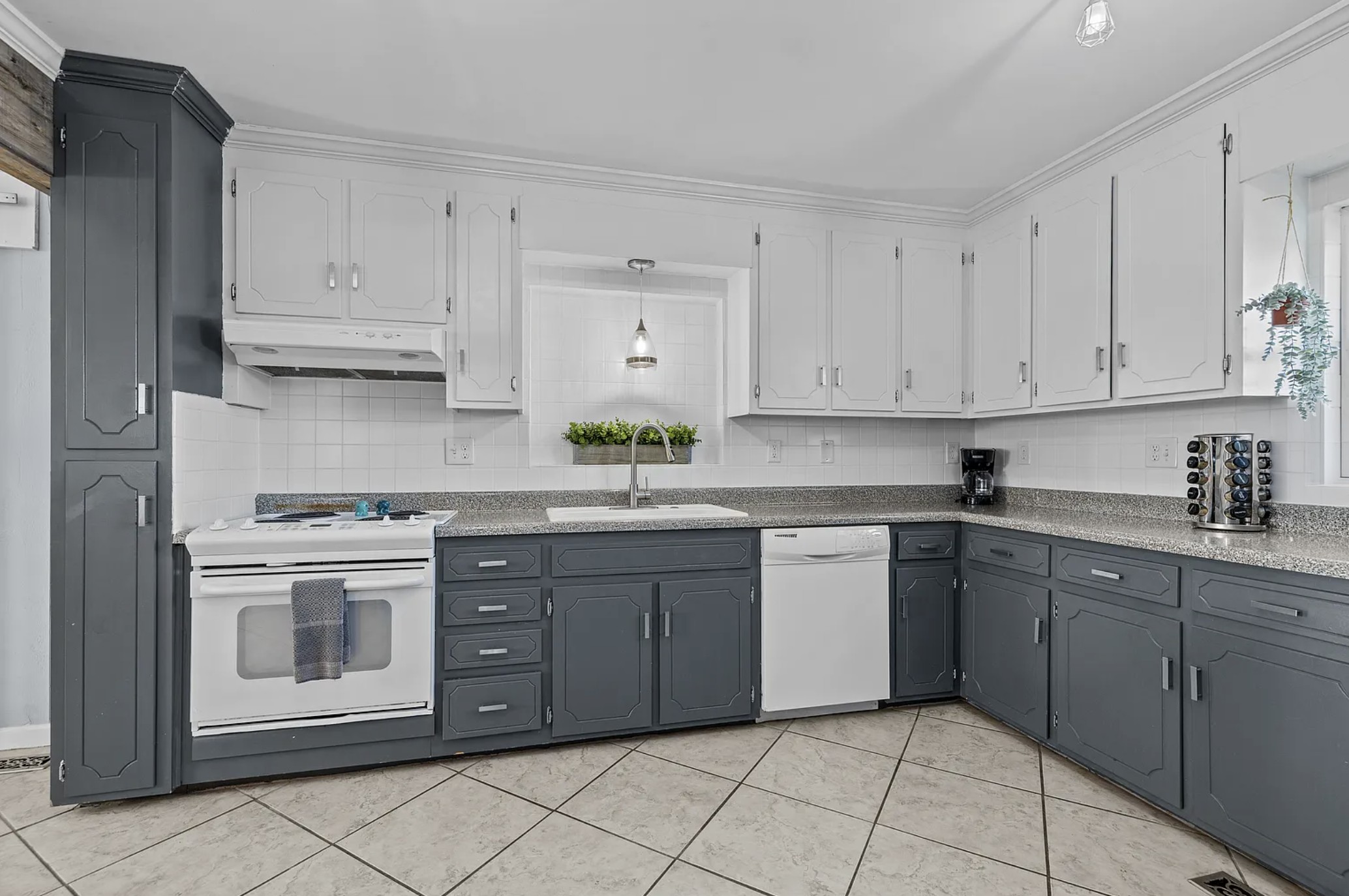 Kitchen counter with white stove, sink, and dishwasher beneath the window
