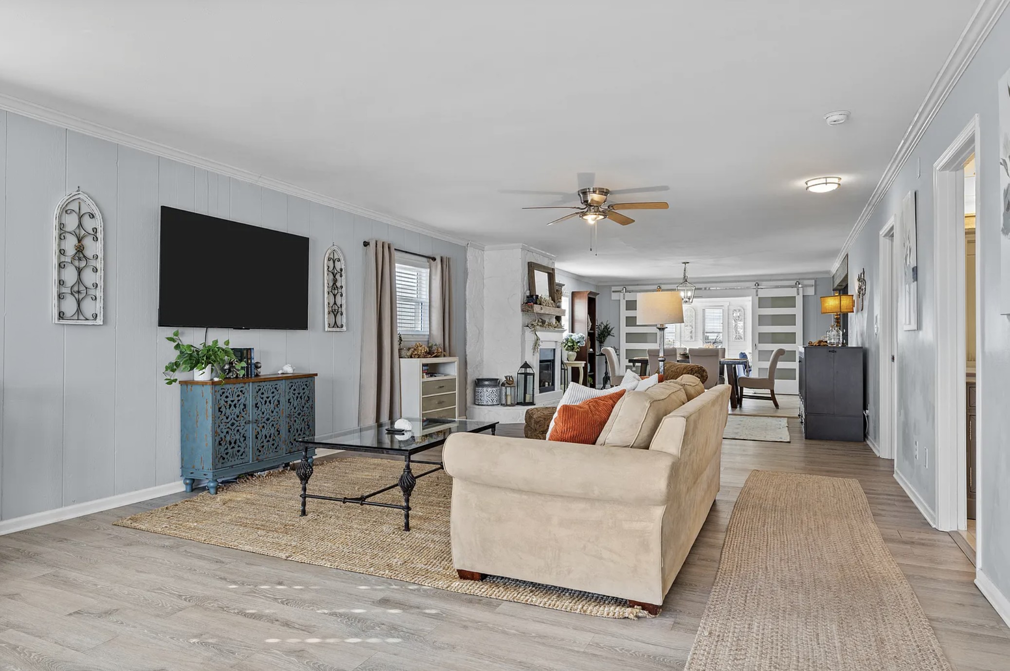 Living room with mounted TV, teal cabinet, and view toward the dining area