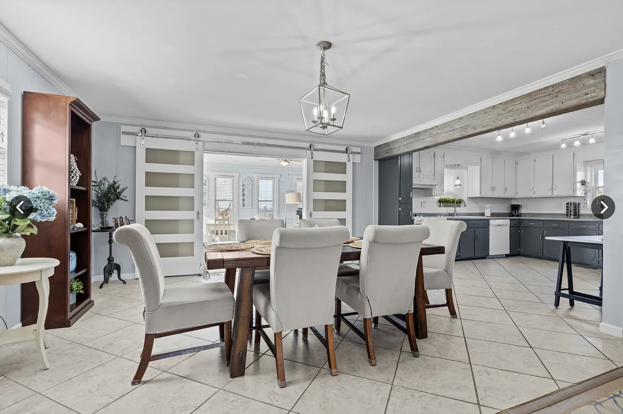 Dining table with upholstered chairs and view to the kitchen through barn doors
