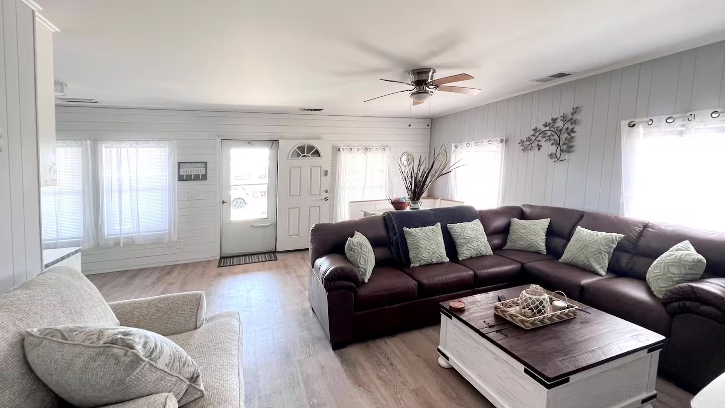 Living room with brown leather sectional, cream armchair, and front entry