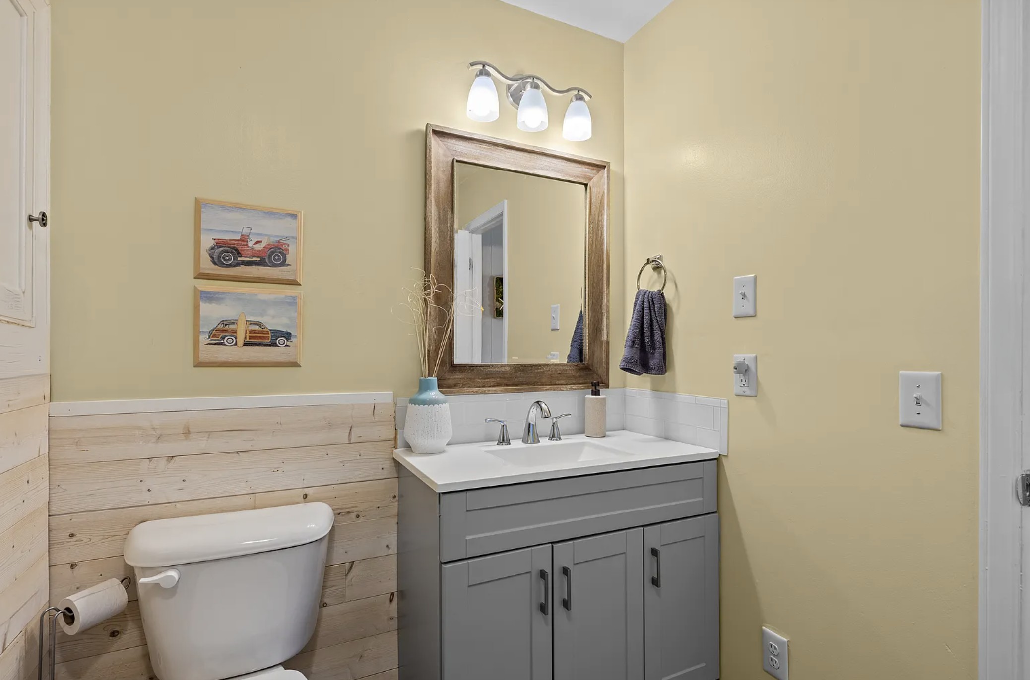 Bathroom vanity with wood-framed mirror and beach art