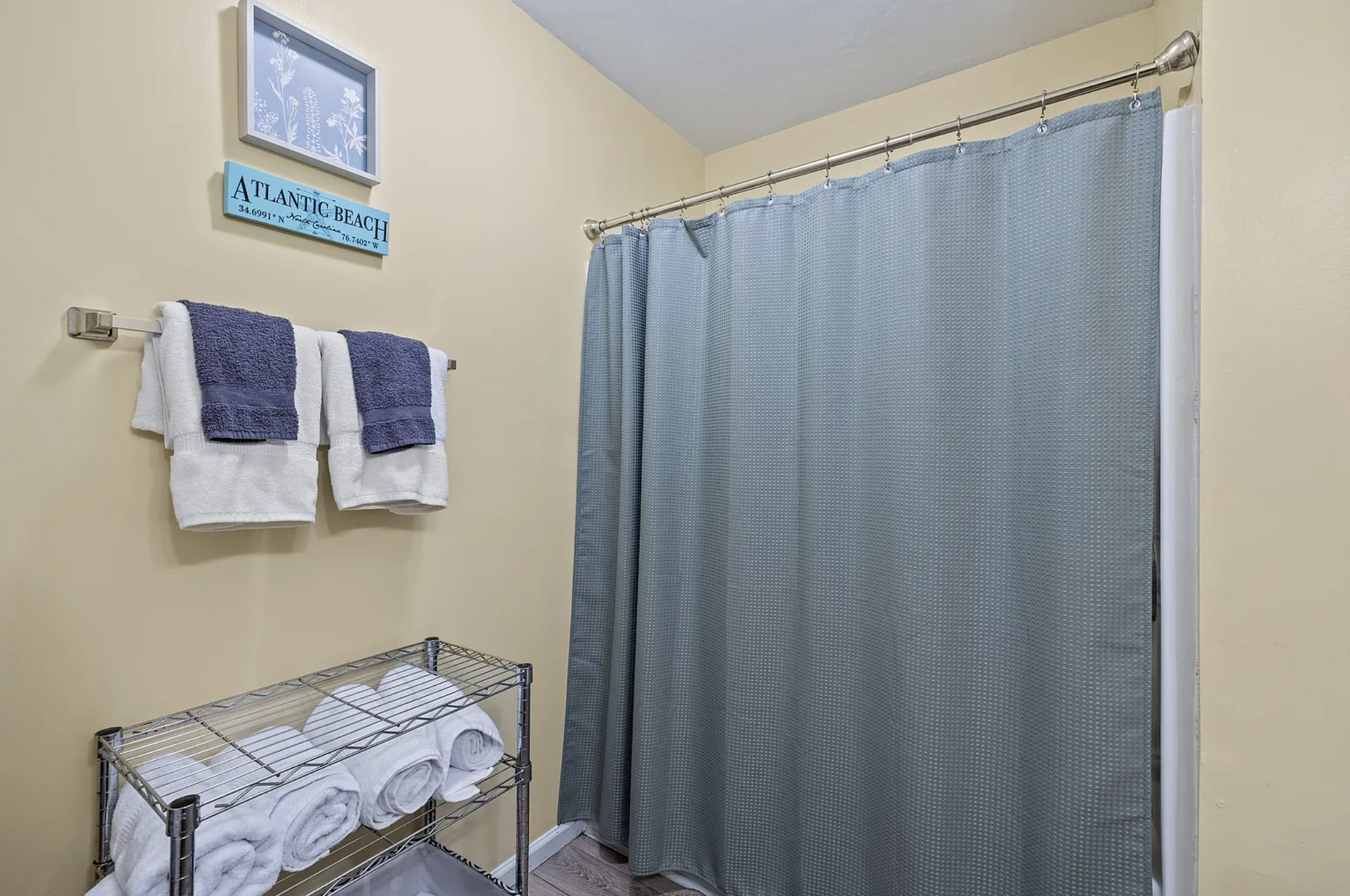 Shower with blue curtain and Atlantic Beach sign on the wall