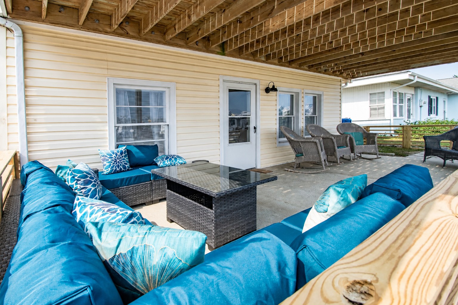 Covered patio with teal wicker sectional and glass-top table