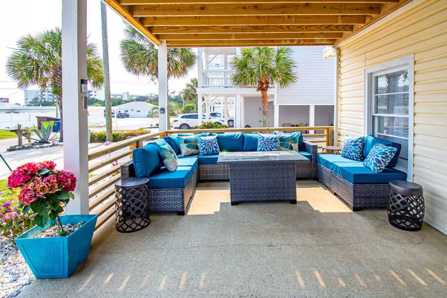 Covered patio seating area with teal cushions and hydrangea planter