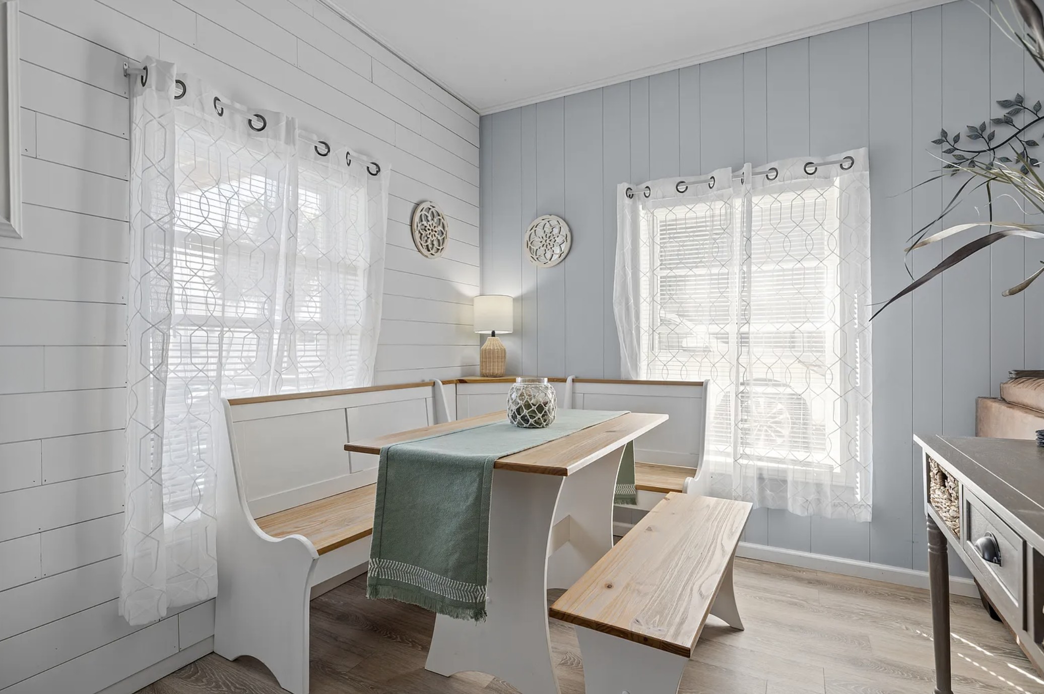 Built-in corner dining nook with white benches and wood-top table