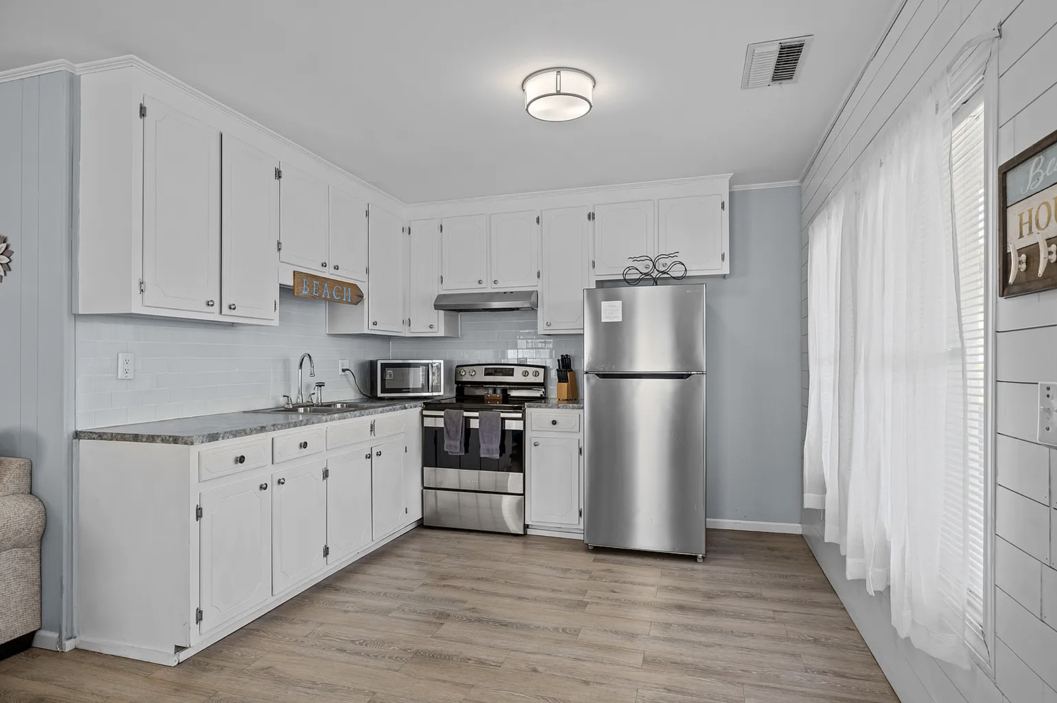 Kitchen with white cabinets, stainless range, and refrigerator