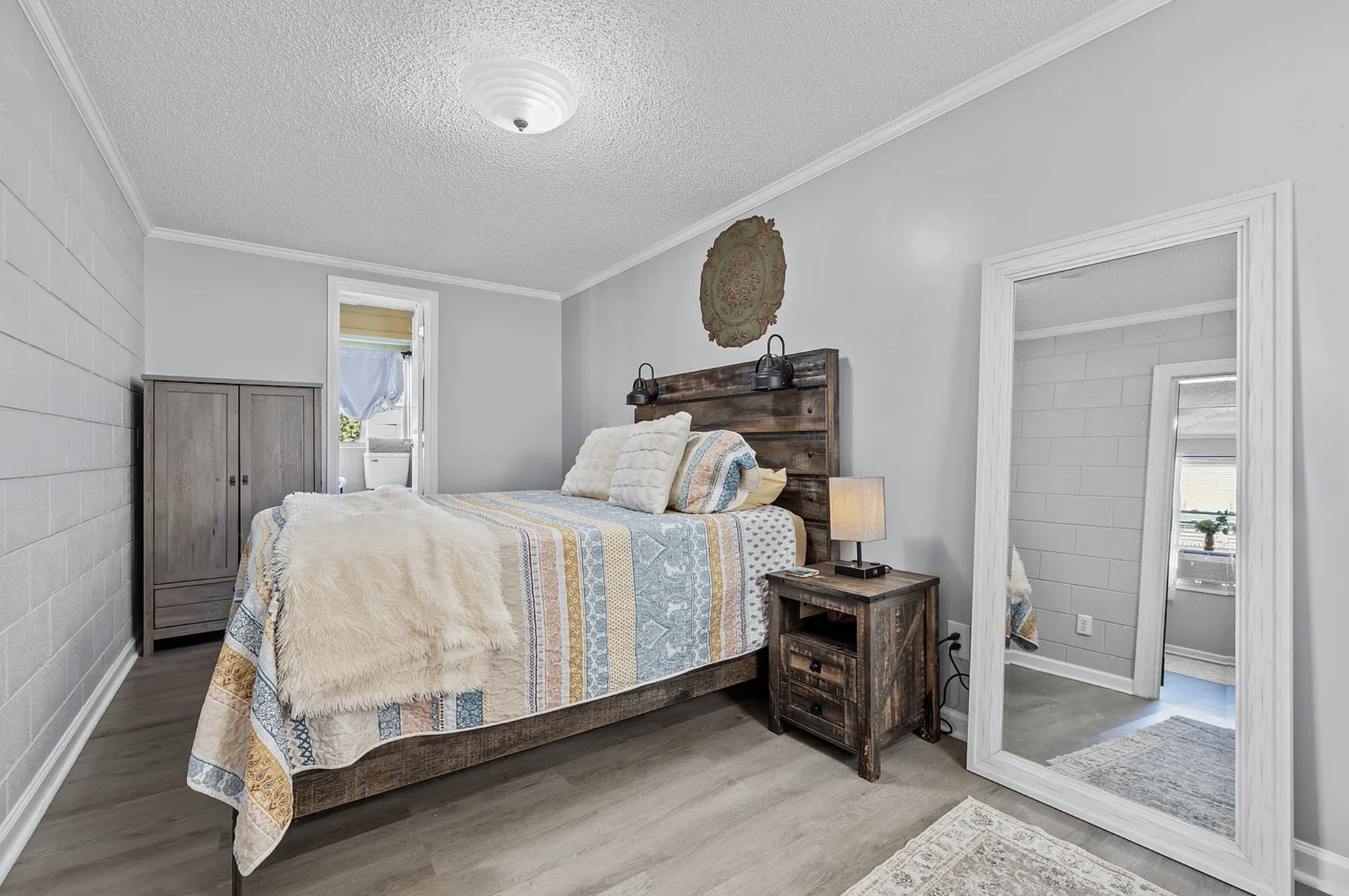 Queen bedroom with wood headboard, armoire, and view to the en-suite bathroom