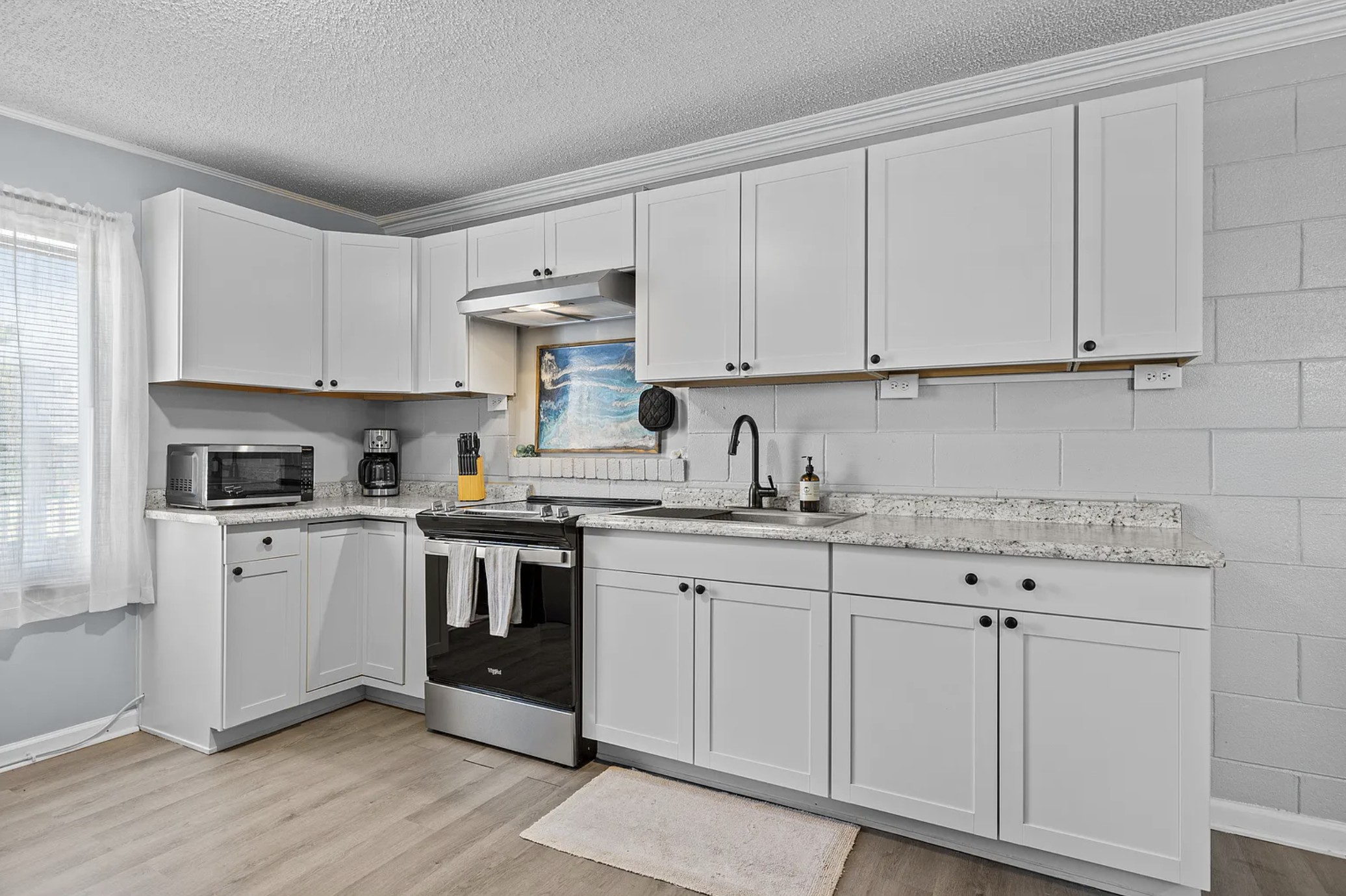 Kitchen with white cabinets, granite counters, and stainless range
