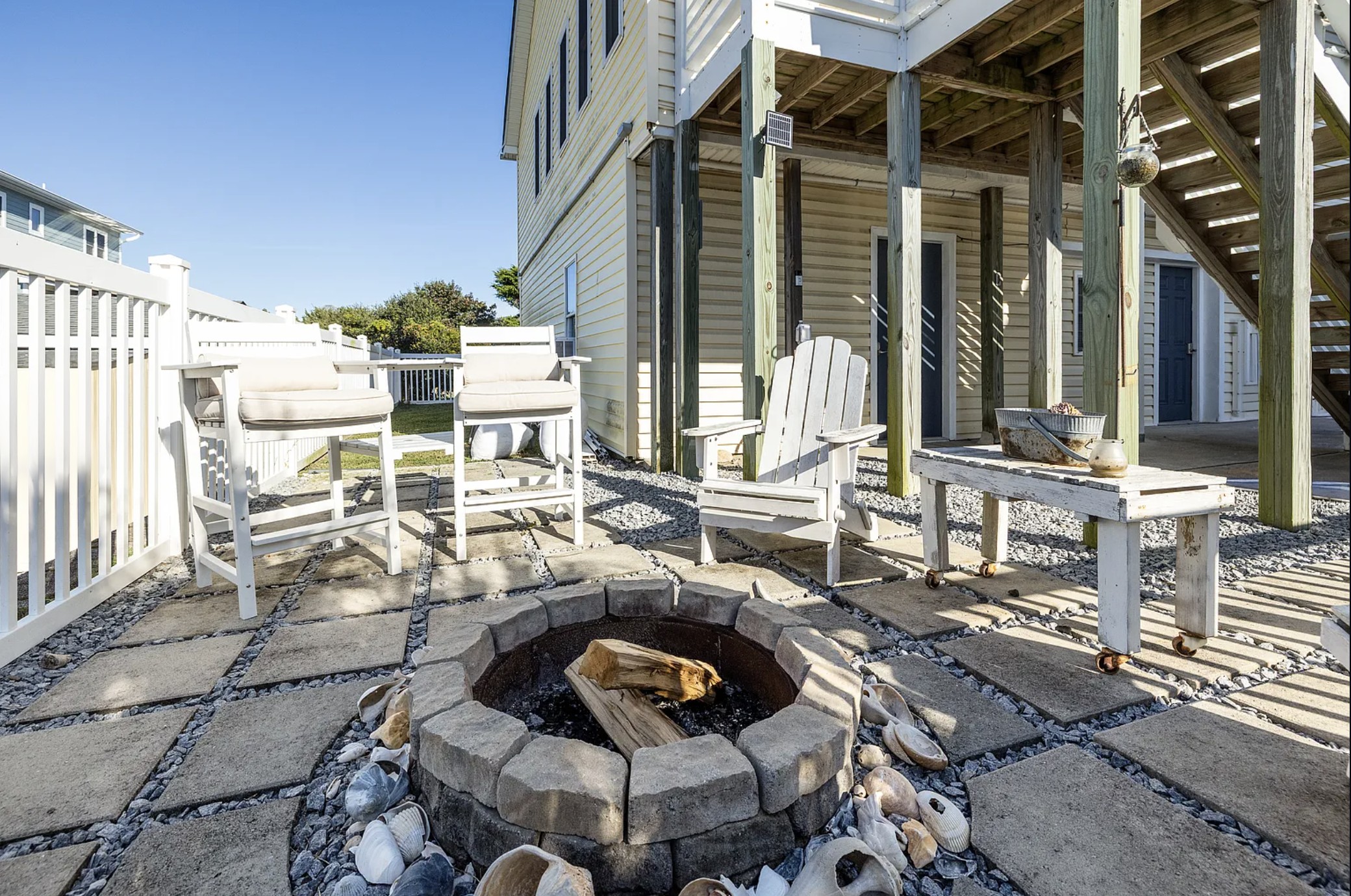 Fire pit patio with white Adirondack chairs and bar-height seating